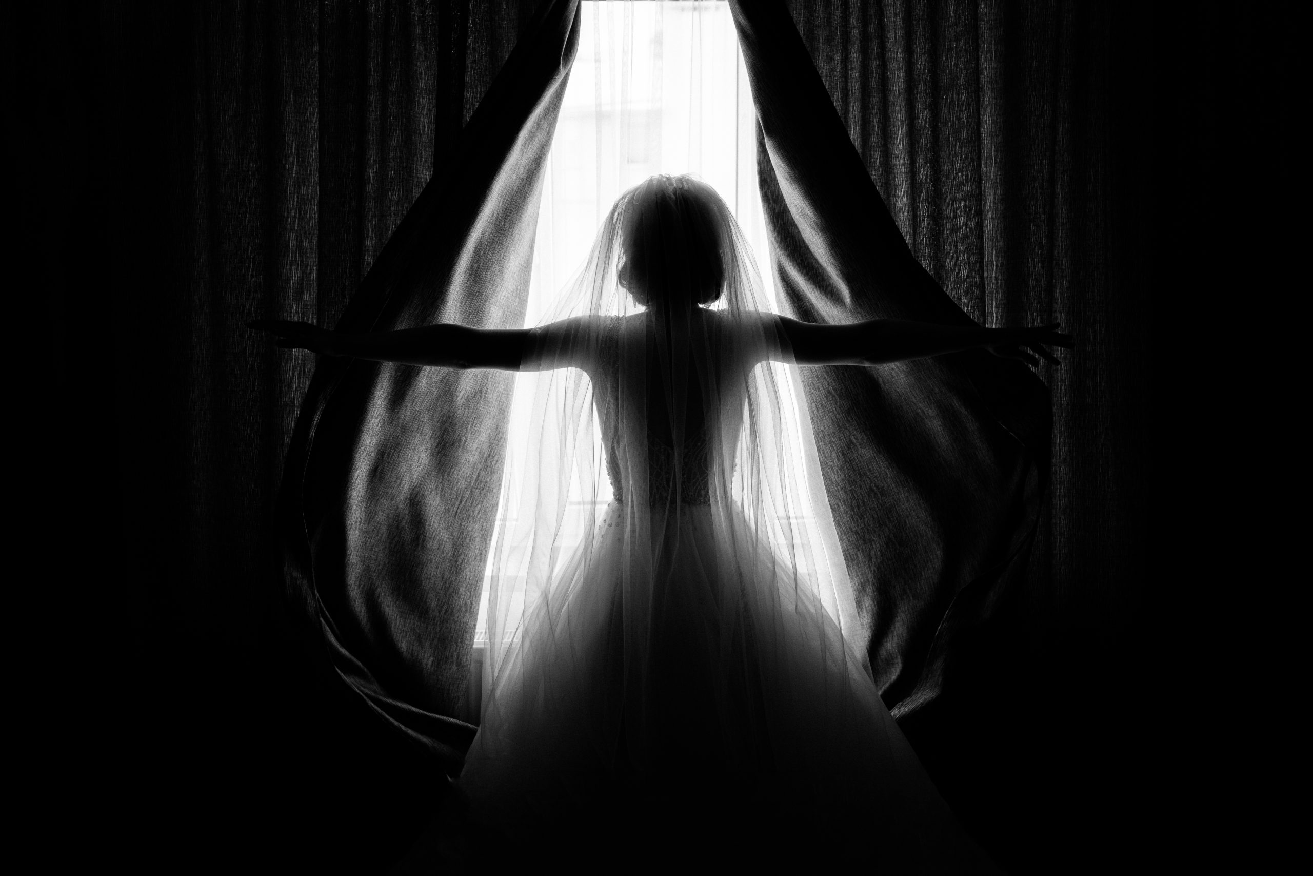Bride opens the curtains in the hotel room